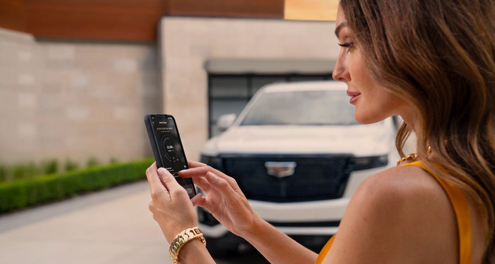 lady checking her mobile with a Cadillac vehicle background | RJ Burne Cadillac in Scranton PA